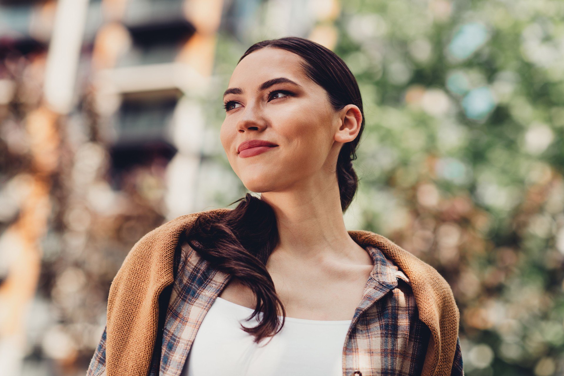 Young woman enjoying a sunny day outdoors with a stylish casual outfit, embracing urban charm, and spreading positivity